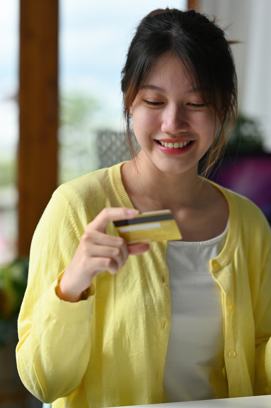 Portrait of young smiling Asian woman holding credit card, cashl